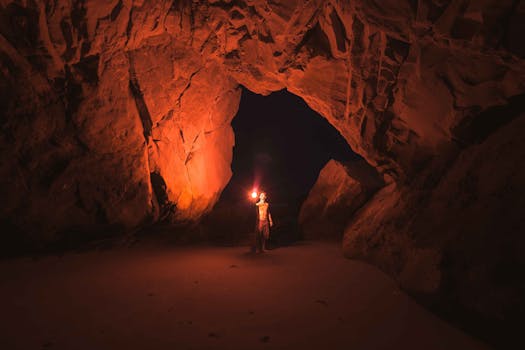 A lone adventurer illuminates a vast Californian cave with a torch at night.
