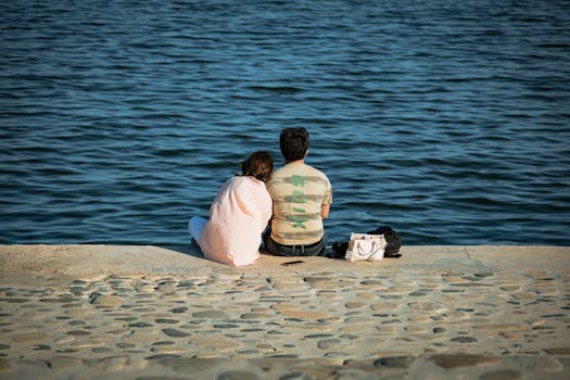 A couple sits by the water's edge, enjoying a peaceful moment together.