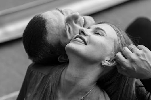 A joyful black and white portrait of a couple smiling closely together, capturing a tender moment.