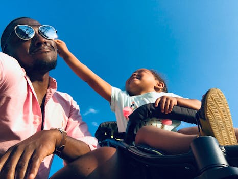 Happy father and daughter bonding moment outdoors under a clear blue sky.