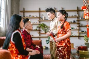Asian family exchanging red envelopes during Lunar New Year celebration indoors.